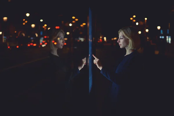 Woman touching sensitive screen of smart city bus stop