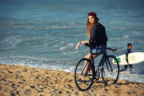 Hipster girl relaxing on the beach wit bicycle