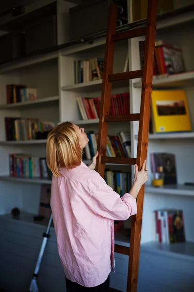 Blonde woman climbing on library ladder