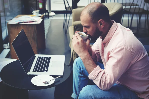 Businessman near laptop drinking coffee