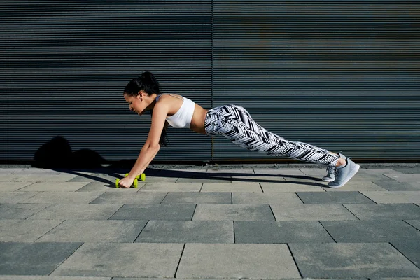 Woman doing press ups with dumbbells