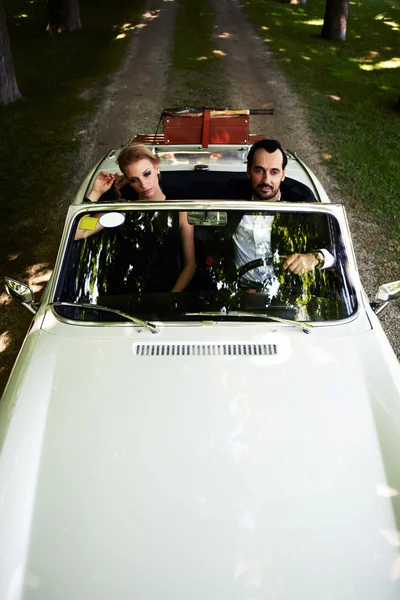 Wealthy and famous couple sitting inside cabriolet