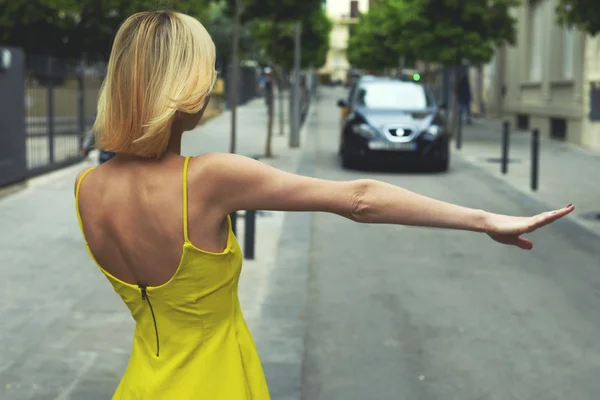 Woman in yellow dress hailing a taxi