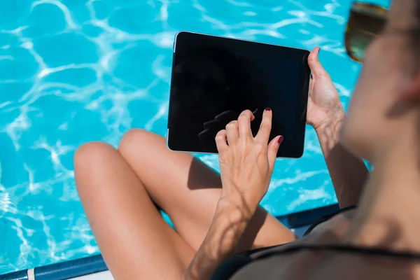 Female in bikini with touch pad near pool