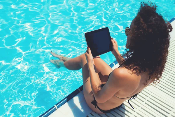 Female in bikini with touch pad near pool