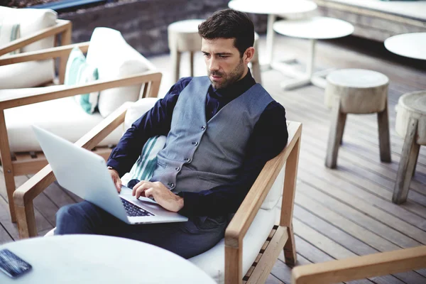 Businessman working on laptop at restaurant terrace