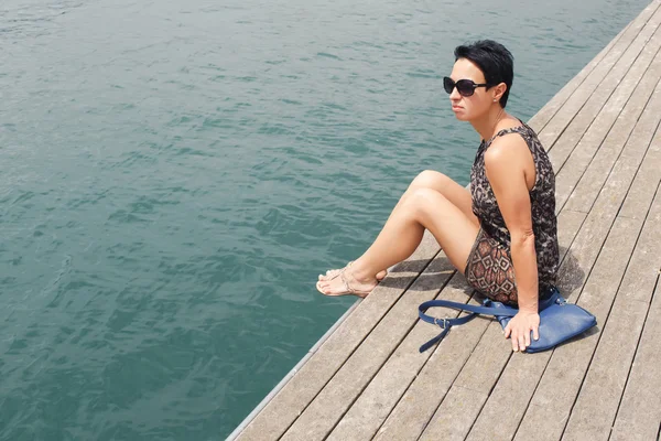 Attractive woman sitting on a wooden pier