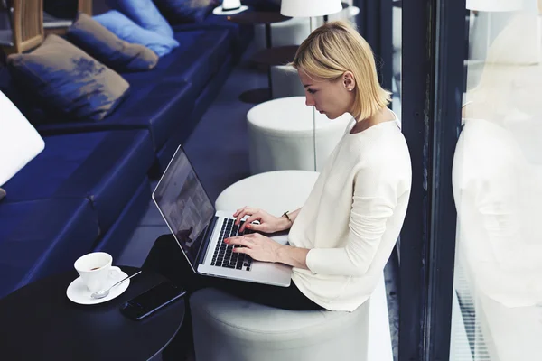 Woman working on net-book in cafe