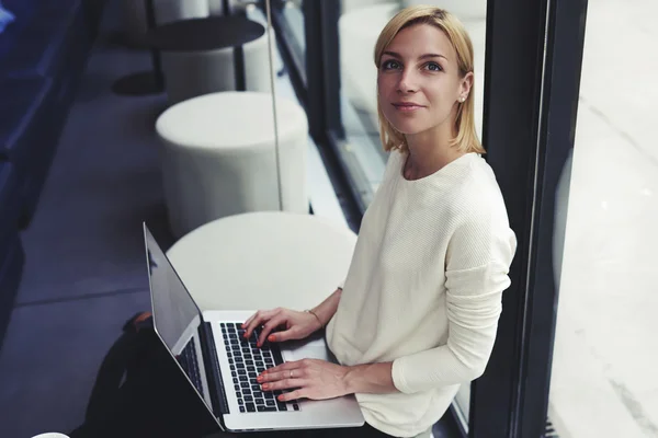 Woman working on net-book in cafe