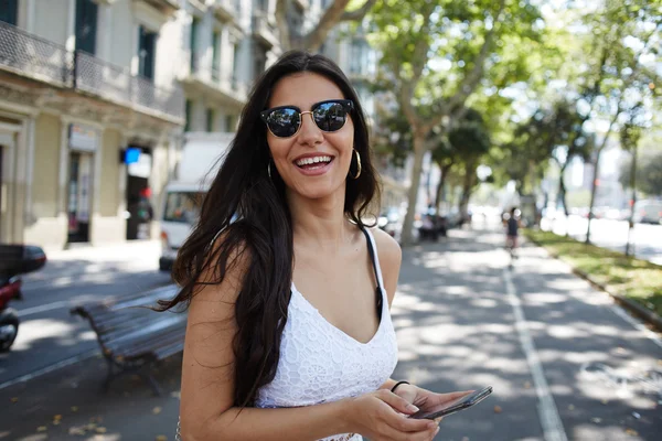 Hispanic woman in sunglasses using smartphone