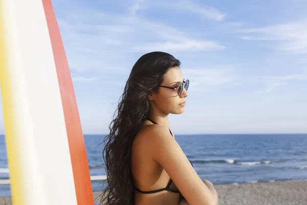 Woman standing with surfboard on the beach