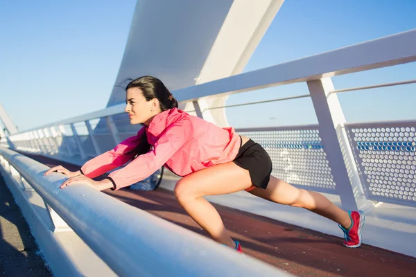 Sportswoman stretching muscles before start