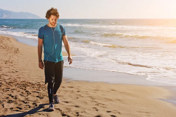 Young sportsman walking along on seashore