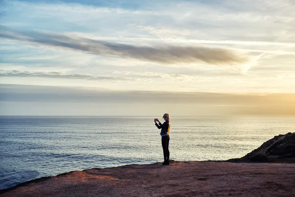 Female taking photo of sea landscape
