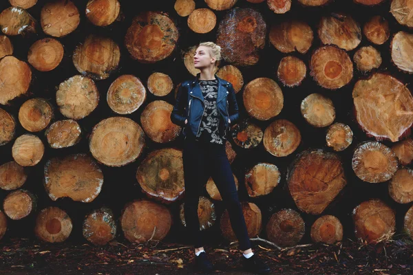 Girl against stacked wooden logs