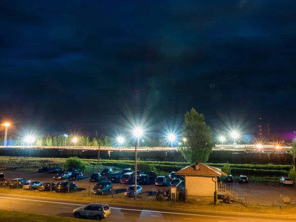 Car parking at night with street lights and dark clouds