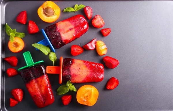 Berry and fruit ice cream pops on black surface