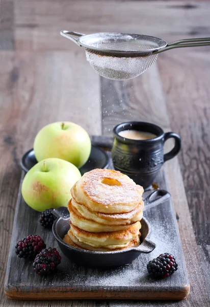 Dusting with icing sugar over apple fritters