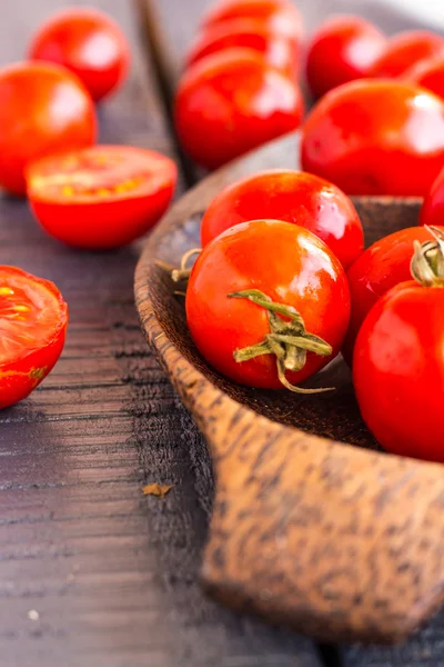 Red juicy tomatoes cherry in brown wooden plate