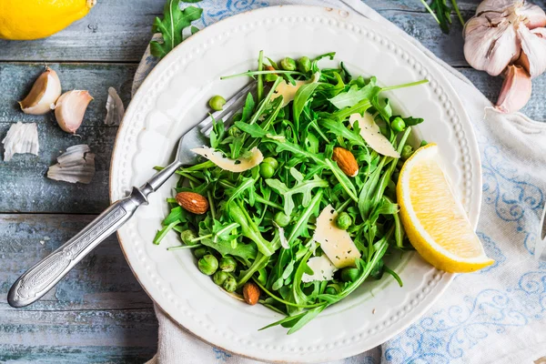 Fresh green salad with arugula, cheese, almonds, lemon and olive