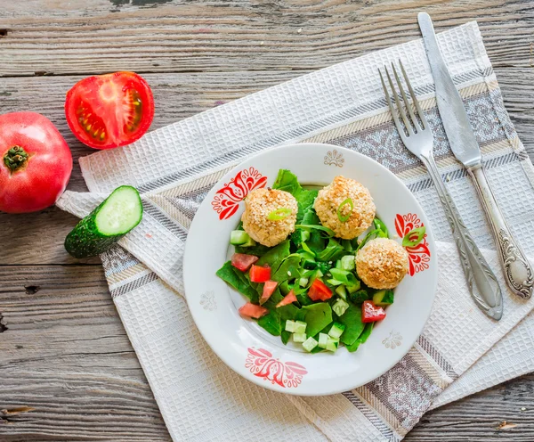 Baked chickpeas balls with sesame and vegetable salad on a gray