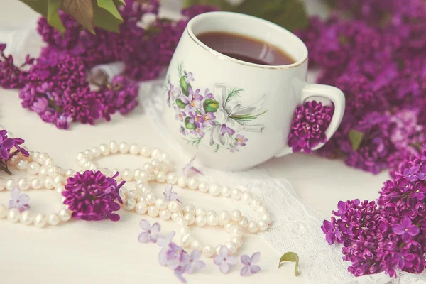 A cup of tea or coffee with a pattern in lilac bouquet of lilacs