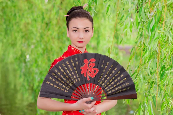 Young Asian girl walking in national dress with a fan near the r