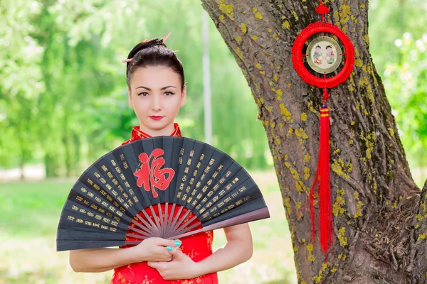 Young Asian girl walking in national dress with a fan in the par