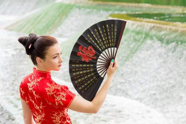 Young Asian girl walking in national dress with a fan near the r