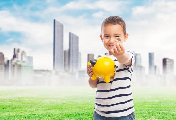 Little boy putting money into piggybank