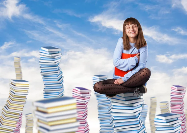 Young woman sitting on books tower