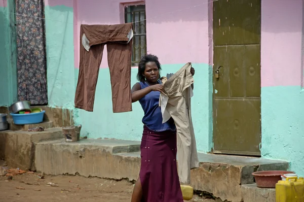 Unidentified woman is hanging her wash outside of her house.