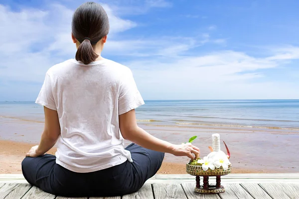 Woman meditating on the beach with flower and herb