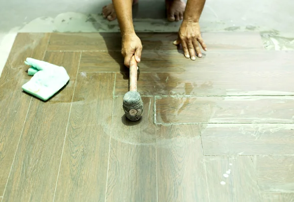 Asian tiler builder installing floor tile
