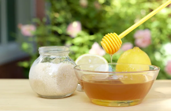 Bowl of honey and sugar and lemons on wooden table
