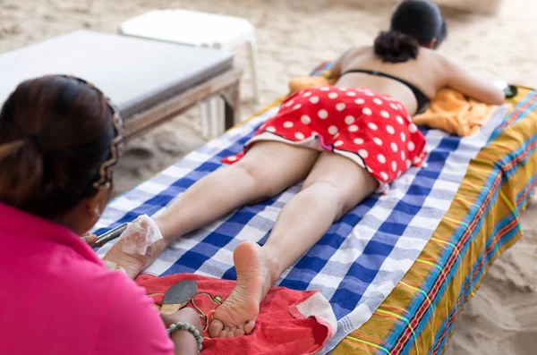 Woman having foot scrub on the beach