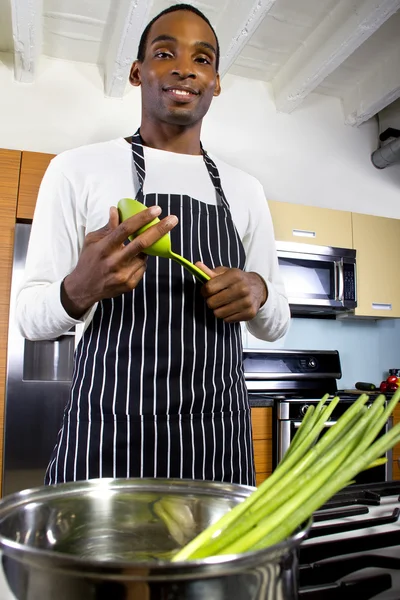 Man wearing an apron and cooking at home