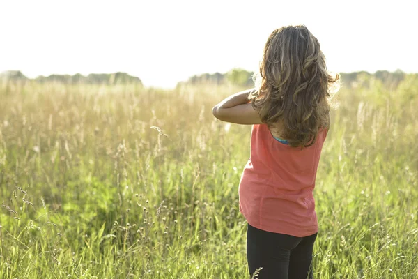 Pregnant girl standing in field straightens hair, a bright sunny day woman waiting for child.