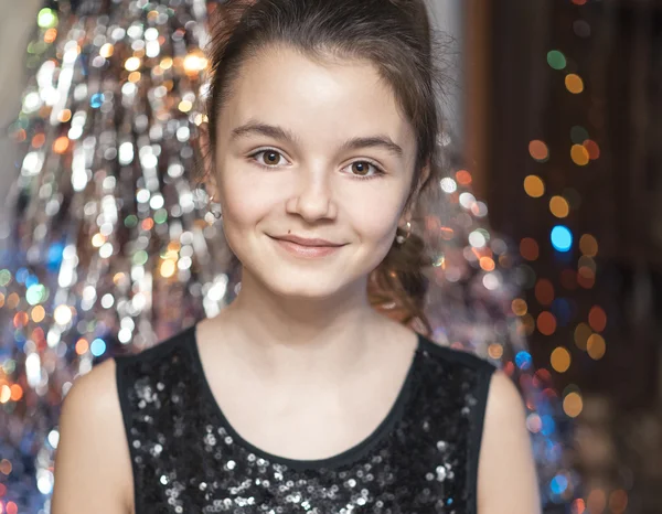 Young beautiful girl smiling and holding a Christmas tree. In black dress happy.