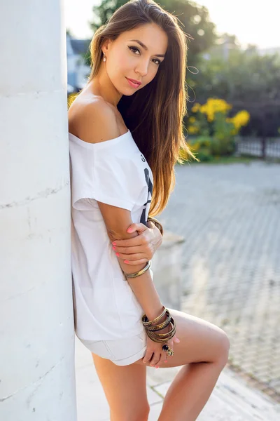 Beautiful young brunette girl posing in a city sunny summer day, happy rest, fashion style, tanned with long hair. Enjoying the .