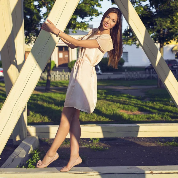 Happy brunette woman in a dress relaxing fun in the park leaning on wooden piles in the  enjoy your vacation, fashion style urban life. Smiling girl bright summer day.