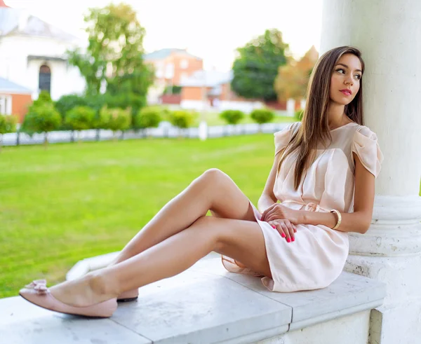 Beautiful brunette girl resting in the open air sitting, dreaming of looking into the distance, business woman with long hair. Fashion lifestyle, glamorous life, student after graduation.