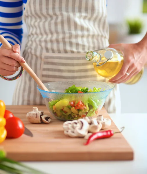 Young woman mixing fresh salad