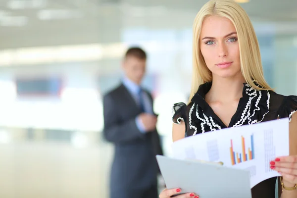 Business woman standing in foreground with a folder in her hands
