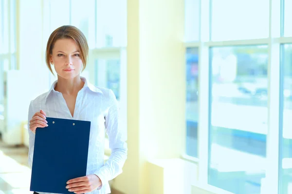 Business woman standing in foreground with a folder in her hands