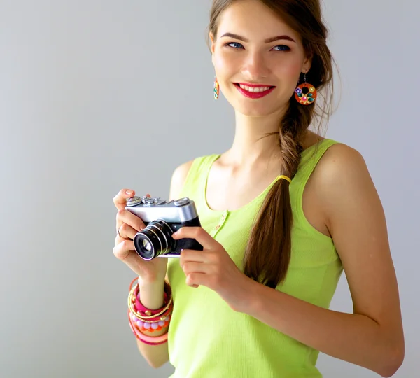 Beautiful young woman with camera standing near window