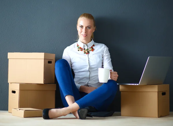 Woman sitting on the floor near a boxes  with laptop