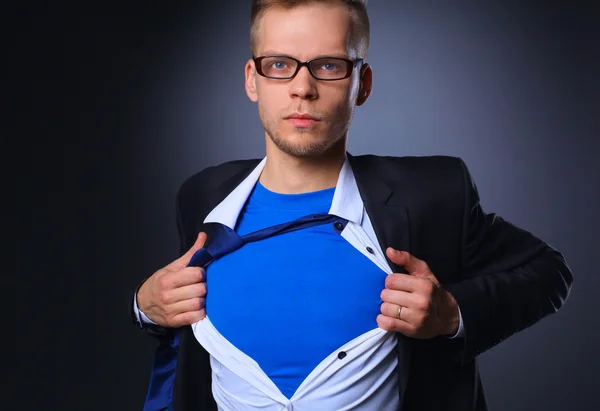 Young businessman acting like a super hero and tearing his shirt, isolated on gray background