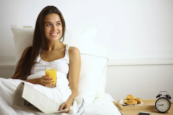 A beautiful woman drinking juice in bed