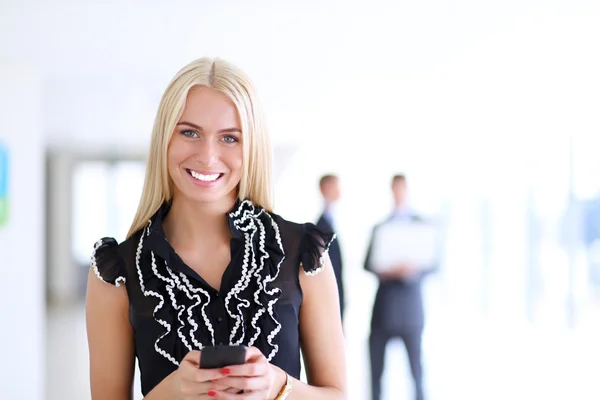 Beautiful businesswoman using cell phone , standing in office